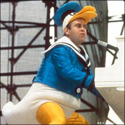 Elton John playing piano while wearing a Donald Duck costume